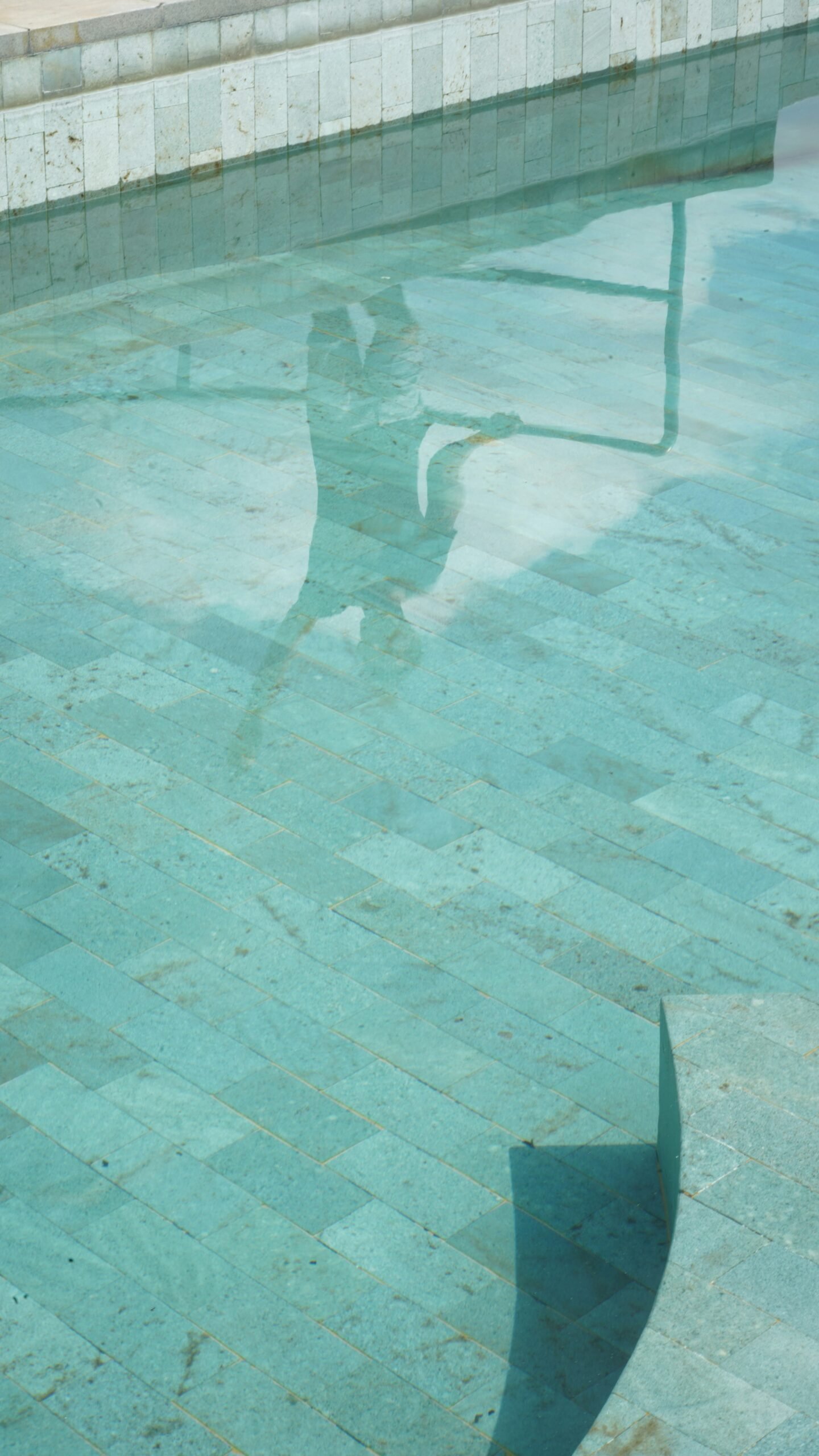 A man sitting on a bench next to a swimming pool